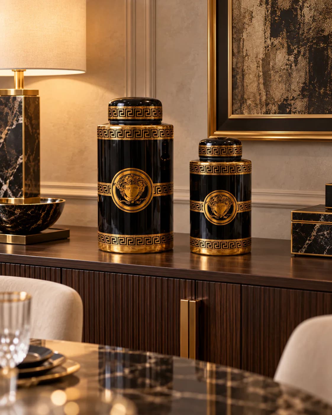 Duo de potiches noir et or sur le buffet d’un salon de villa, à côté d’une lampe en marbre noir