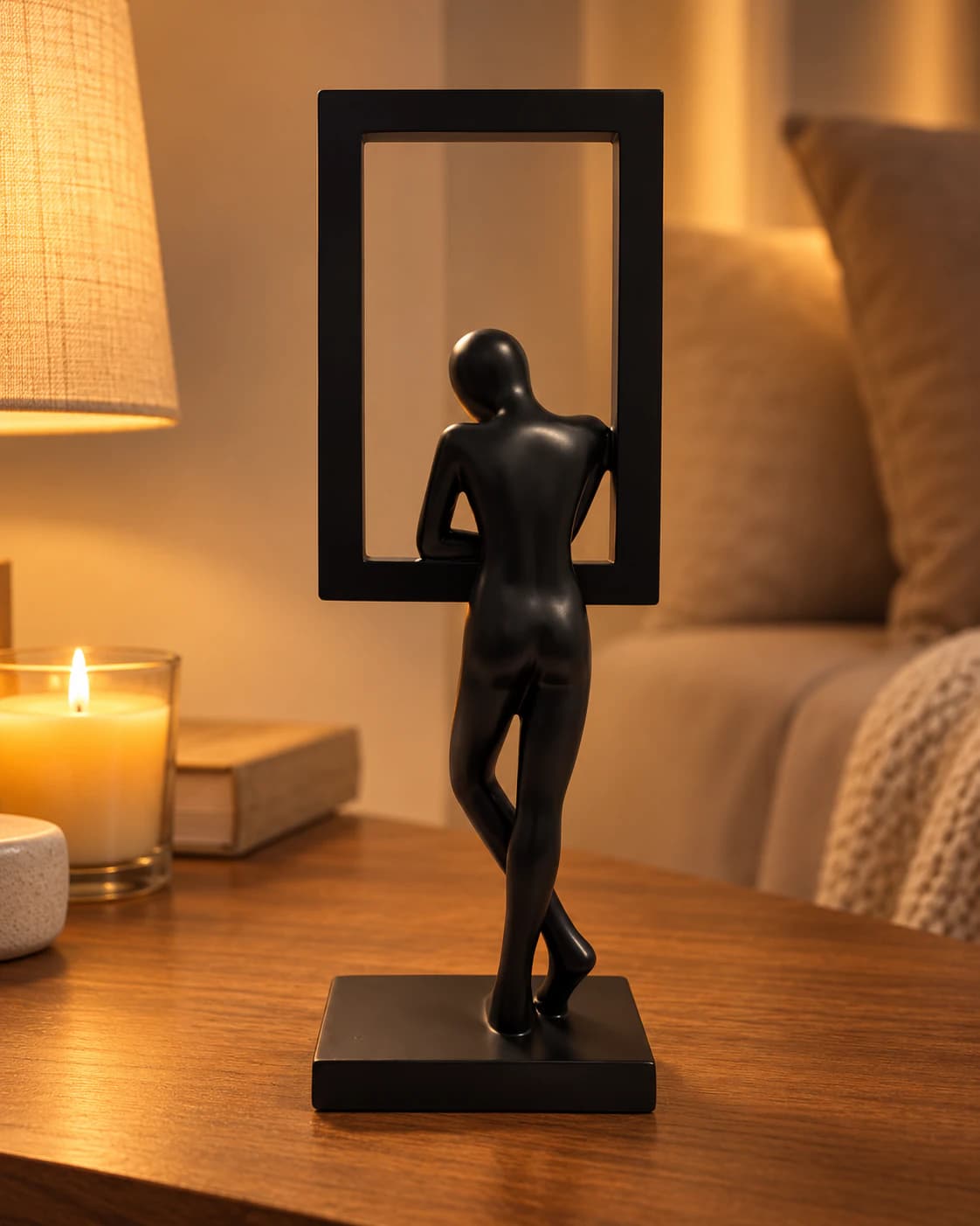 Sculpture noire du penseur dans son cadre, vue de dos, sur un meuble en bois éclairé par une lampe