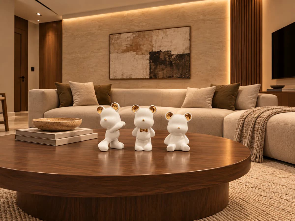 Trio d’ours en céramique blanc et or sur une table basse ronde dans un grand séjour aux tons clairs